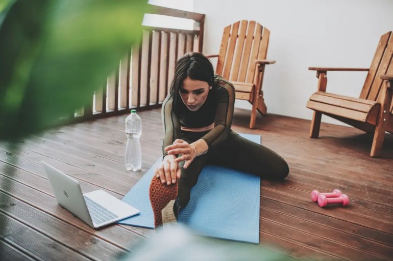 young woman working out from home using fitness apps on computer